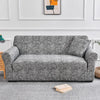 A gray elastic sofa cover protector with a fine crackle pattern displayed on a sofa.
