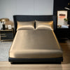 A luxurious gold satin bedding set displayed on a modern black bed with matching pillows and a fitted sheet.