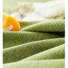 Close-up of textured olive green cotton tassel table runners with a yellow accent.