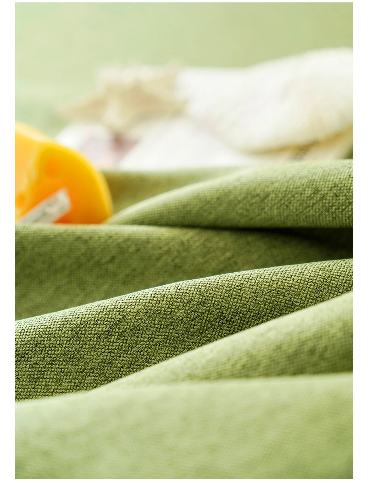Close-up of textured olive green cotton tassel table runners with a yellow accent.