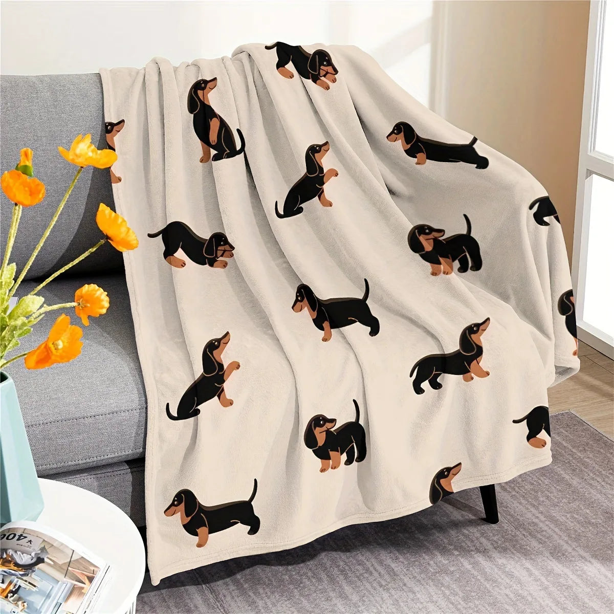 A beige flannel blanket featuring a repeating pattern of black dachshund silhouettes.