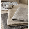Close-up of a beige linen sofa cover cushion showing the woven texture and stitching detail.