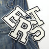 White letter patches spelling out LRS scattered on a denim fabric background