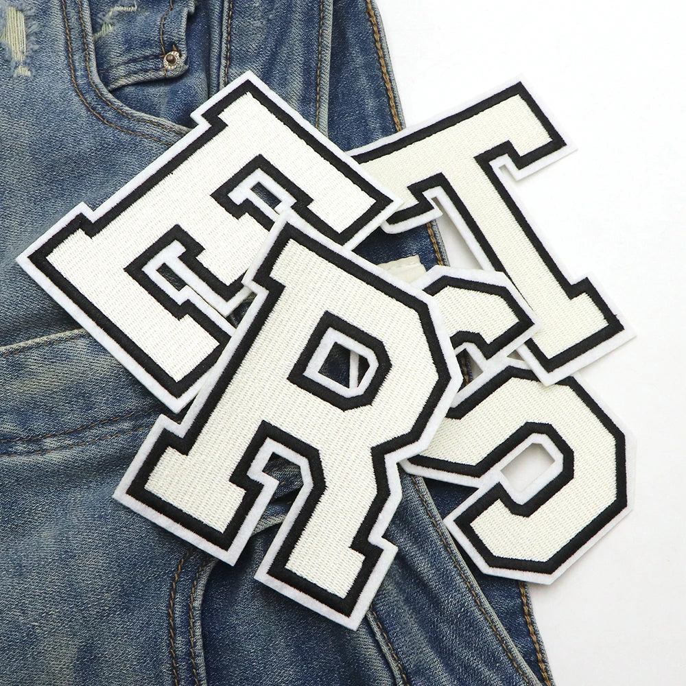 White letter patches spelling out LRS scattered on a denim fabric background