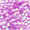 A close-up of small, iridescent pink and purple acrylic heart beads for jewelry making.