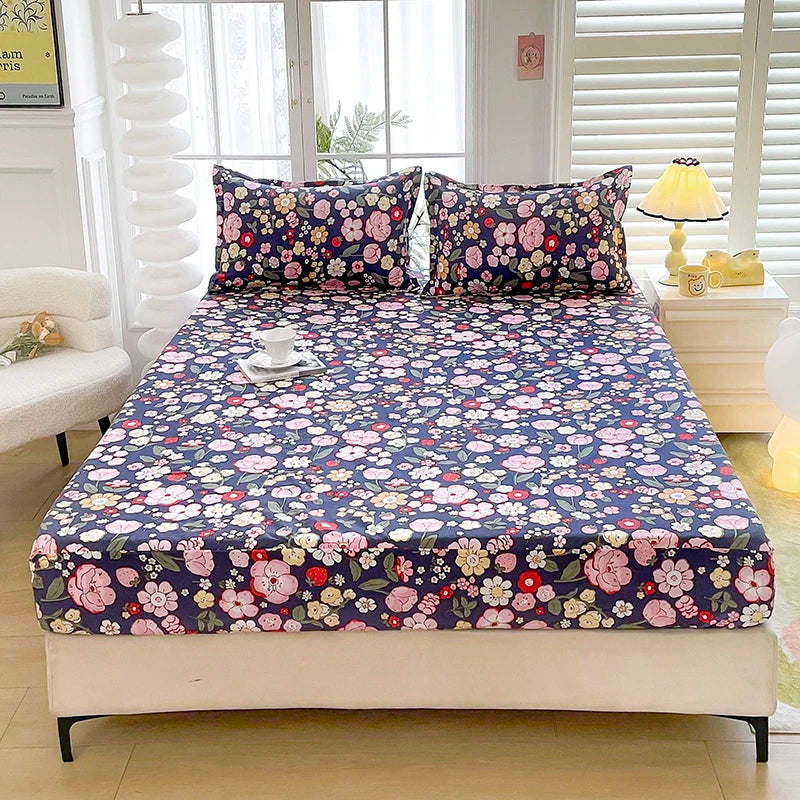 A fitted bed sheet with a dark blue floral print is displayed on a white bed frame in a bright room.