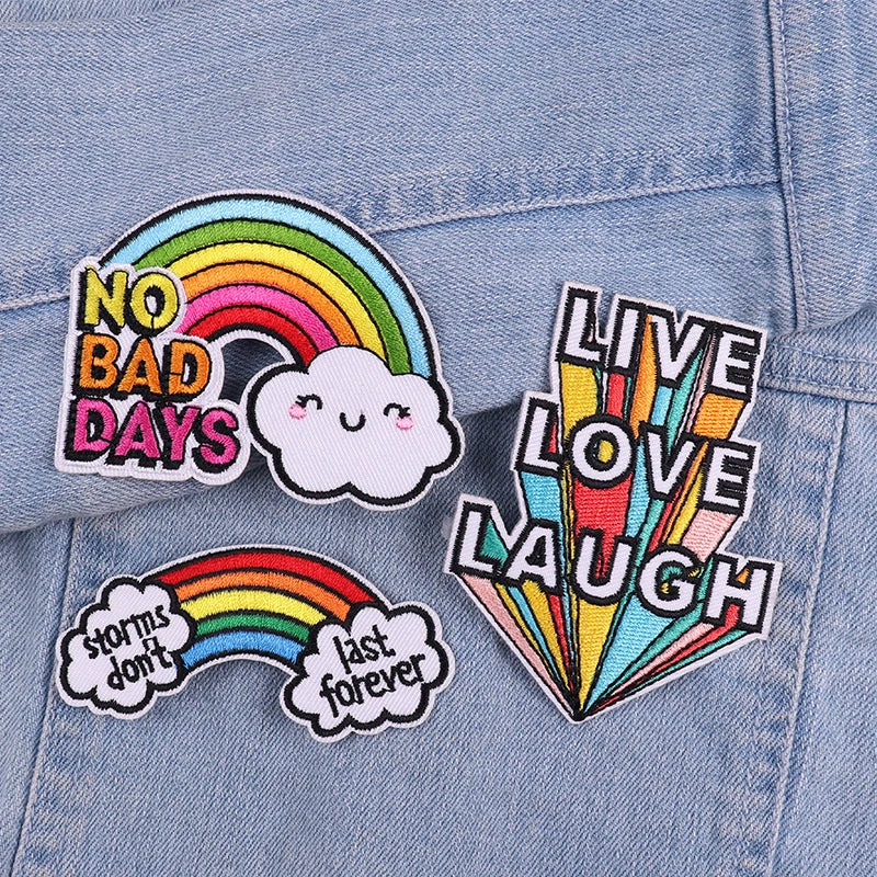 Three embroidered patches featuring rainbows and clouds with text like No Bad Days and Storms Don't