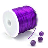 Purple elastic beading cord on a spool with loose strands nearby