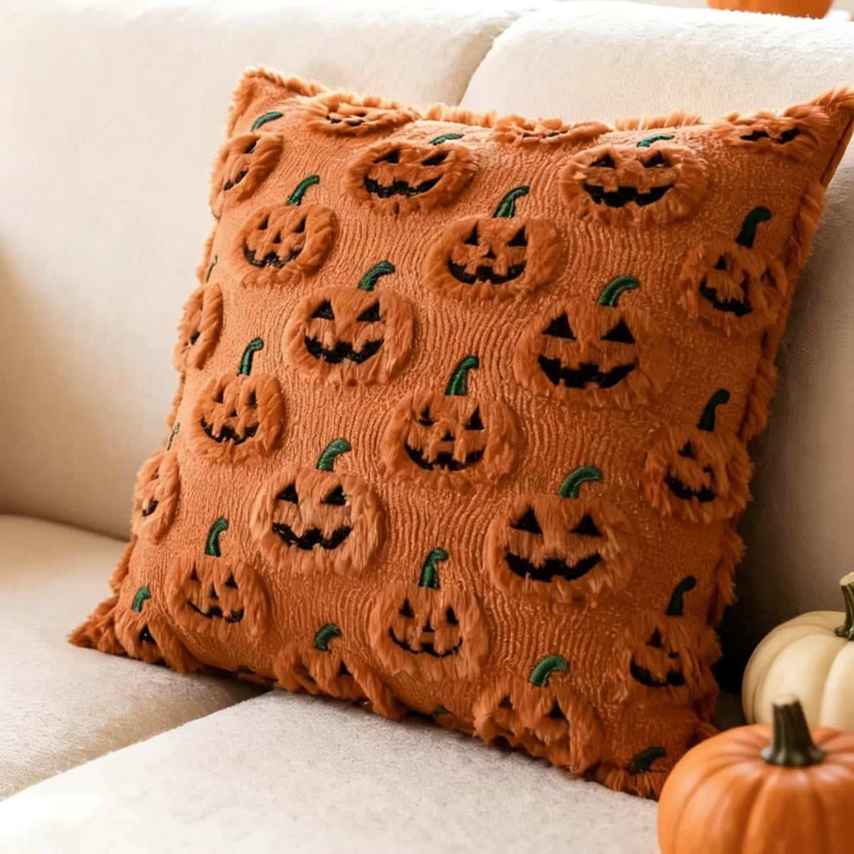 A brown fuzzy throw pillow covered in small carved jack-o'-lantern faces.