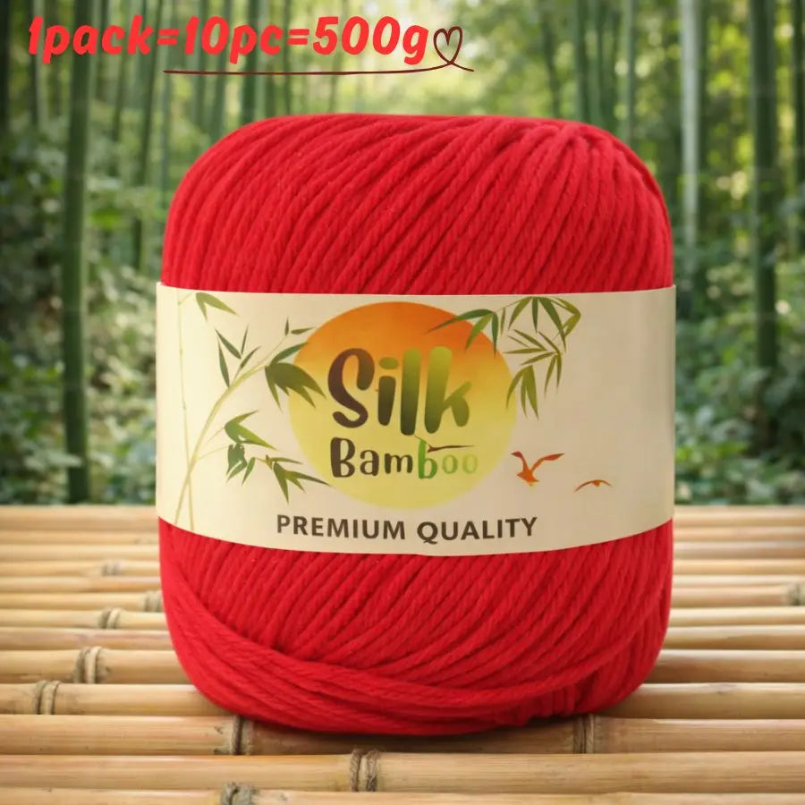 A red ball of silk bamboo blend yarn with a label indicating premium quality is shown on a wooden surface.