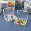Various colorful nickel-plated dressmaking pins with various colored heads are displayed in clear plastic boxes.