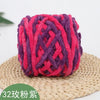A ball of magenta and purple chenille knitting yarn resting on a woven straw mat.