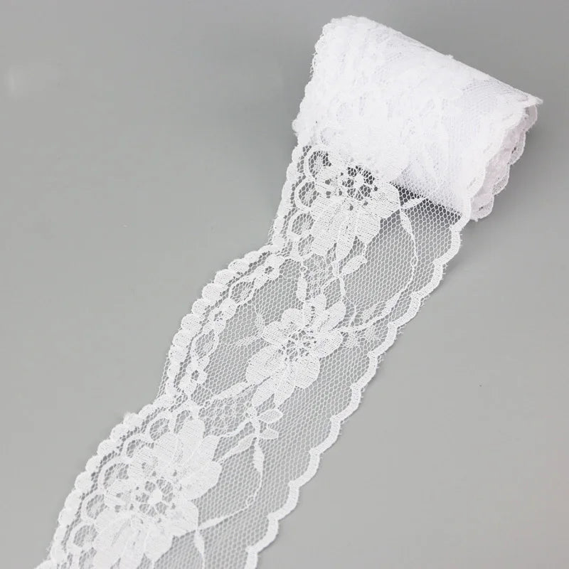 A roll of white decorative lace ribbon, approximately 65mm wide, shown against a light gray background.