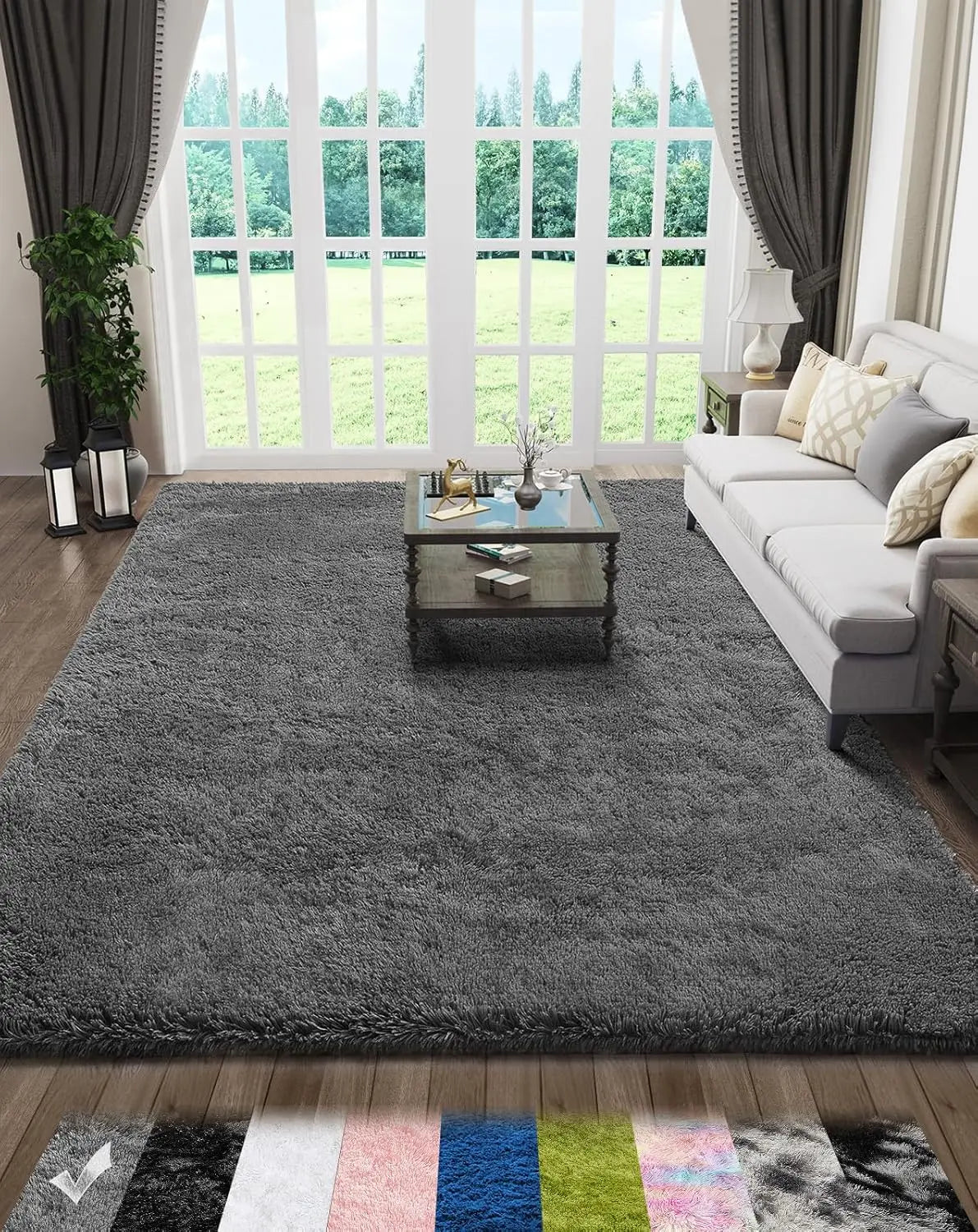 A gray plush floor mat placed on a wooden floor in front of a large window with greenery visible outside.
