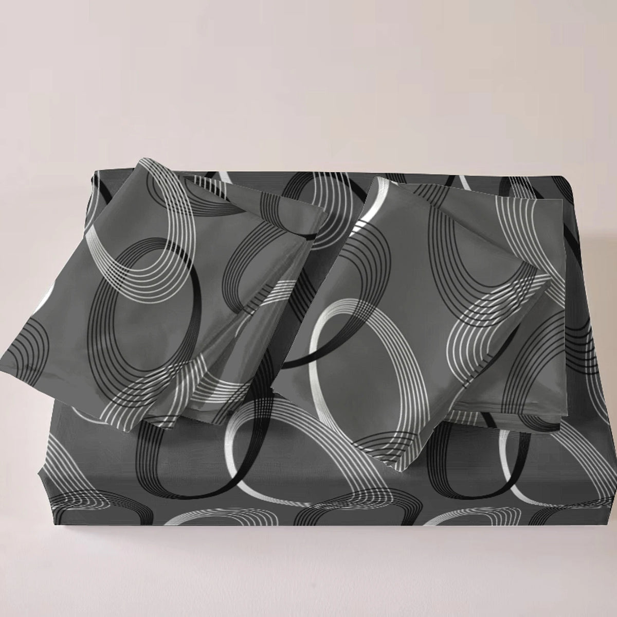 A set of three printed quilts featuring overlapping concentric circles in shades of gray and white.
