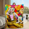 A woman wearing a pink top and yellow overalls is posing with an ultra-soft flannel throw blanket featuring a colorful geomet