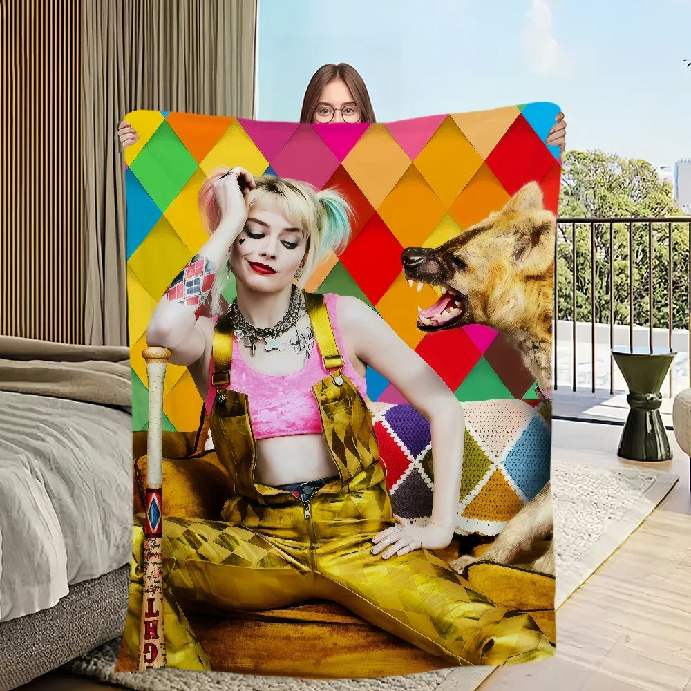 A woman wearing a pink top and yellow overalls is posing with an ultra-soft flannel throw blanket featuring a colorful geomet