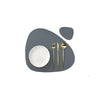 A set of reusable vinyl placemats featuring a white plate and gold cutlery on a gray background.