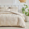 A beige embossed leaf duvet cover set displayed on a bed with white headboard and natural light.