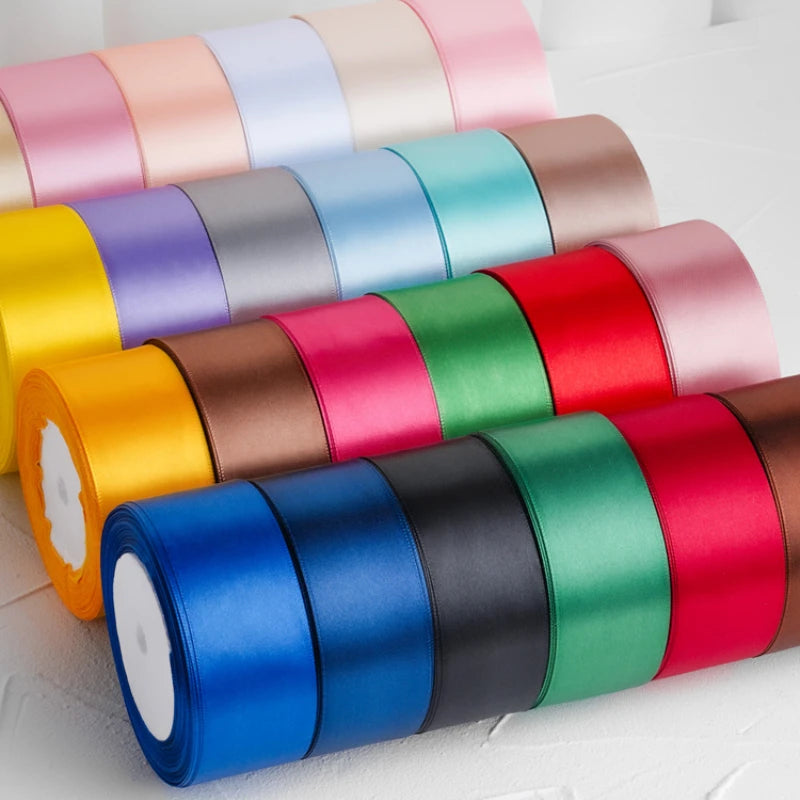 A collection of rolled satin craft ribbons in various colors including pink, blue, green, yellow, and red.