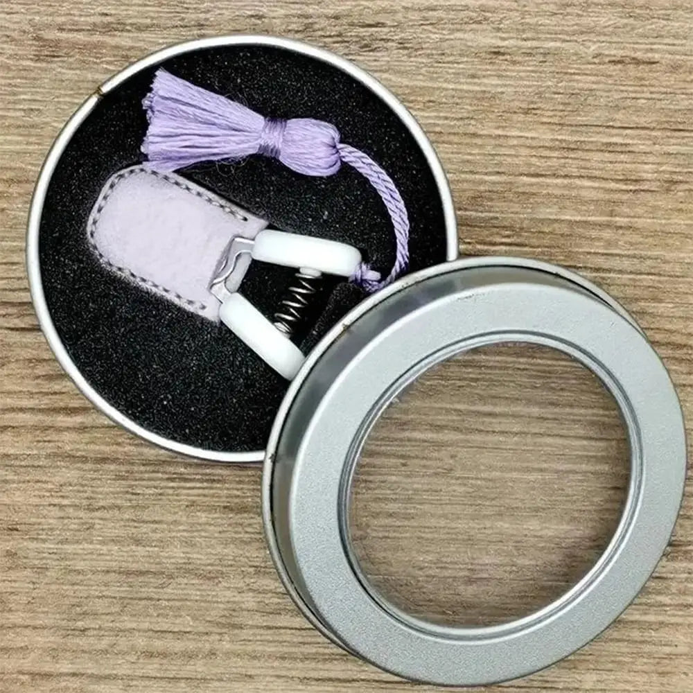 Mini precision sewing scissors with a lavender protective cover and purple thread on a wooden surface.