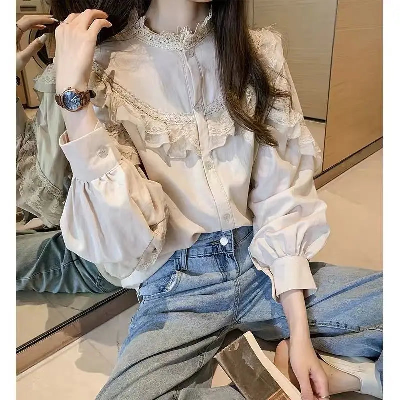 A woman models a cream lace long sleeve blouse and blue jeans in a studio setting.