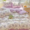 A lavender print duvet cover set and pillows featuring small purple flowers on a pink background.