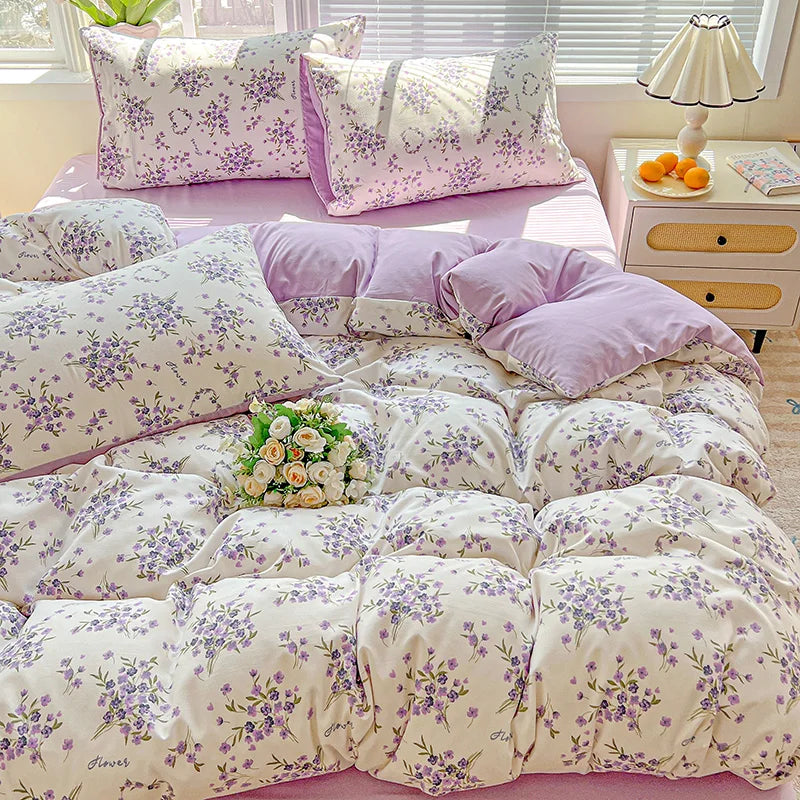 A lavender print duvet cover set and pillows featuring small purple flowers on a pink background.