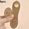 A hand holds a set of eight tan leather bag buttons, showing the texture and gold accents.