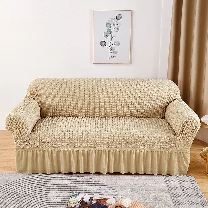 A beige stretch knit sofa cover featuring a bubble lattice texture displayed on a light-colored floor.