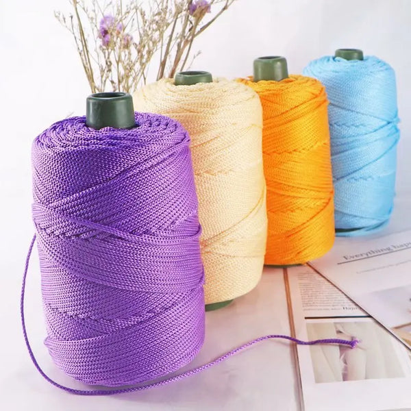 Purple crochet ice rope spool next to yellow and orange colored ropes on a white surface.