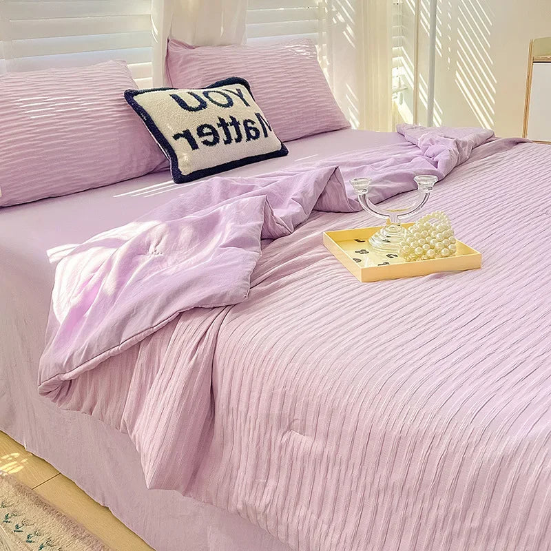 A pink Korean style seersucker summer quilt set with white striped bedding and a black embroidered pillow.