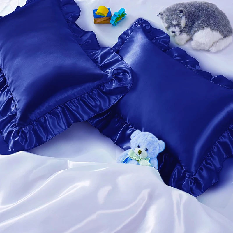 A set of two royal blue ruffled satin pillowcases with silky envelope closures and a small stuffed animal