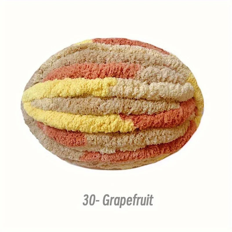 A round, hand-knitted yarn in horizontal stripes of peach, yellow, and pink tones.