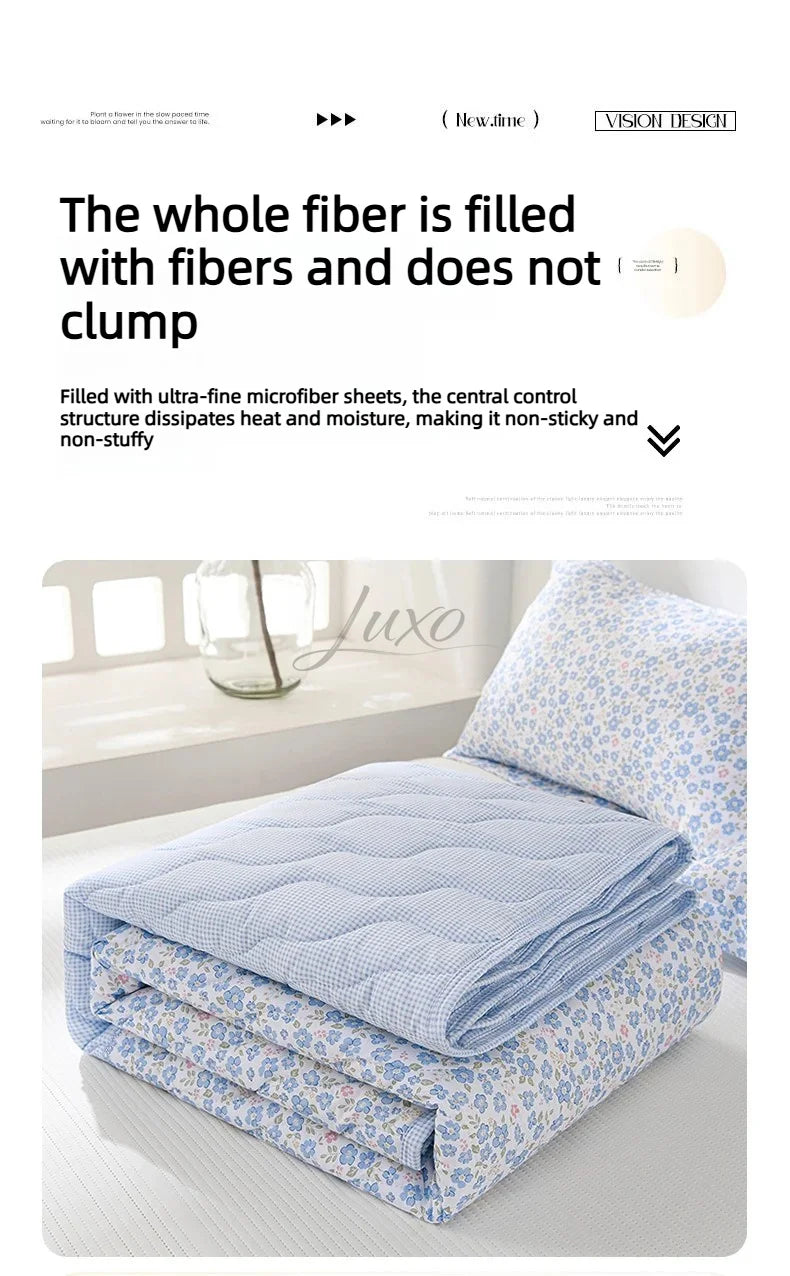 A light blue quilted quilt set with a floral pattern is displayed on a bed.