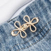 Gold adjustable leaf clover waist tightener jewelry resting on blue denim fabric