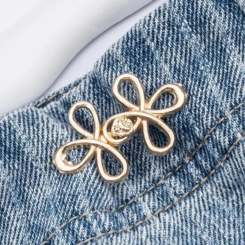 Gold adjustable leaf clover waist tightener jewelry resting on blue denim fabric