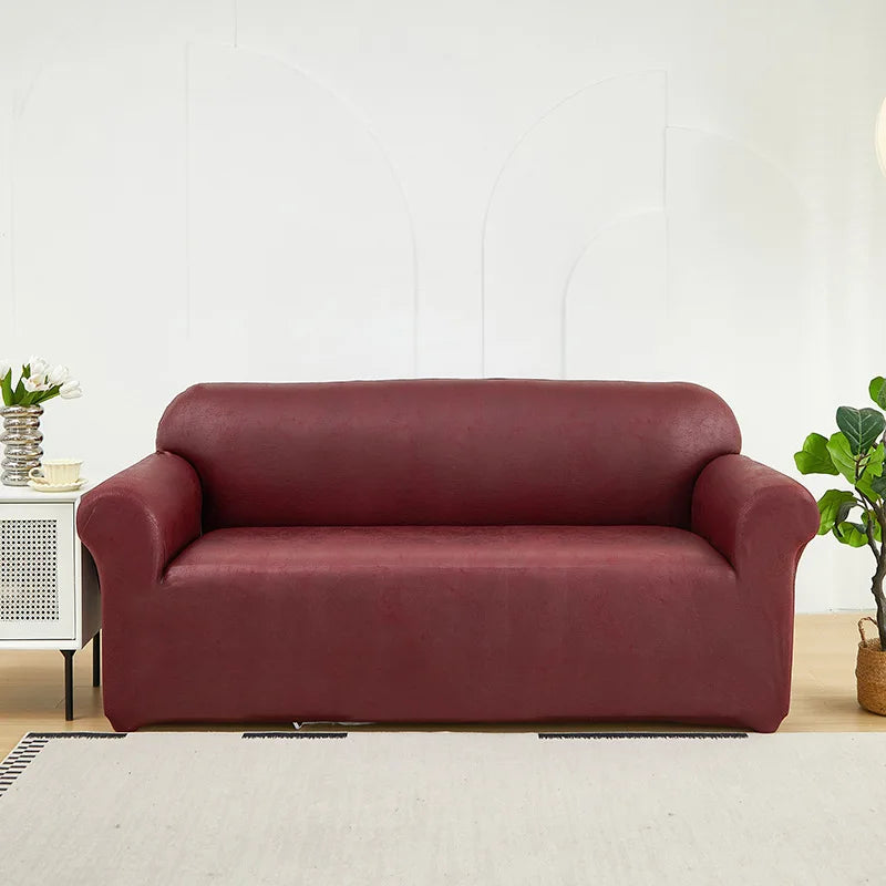 A deep burgundy PU leather sofa slipcover in a modern style placed in a bright living room.