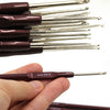 A hand holds a set of 16 ergonomic crochet hooks with soft-grip handles, showing the size and color.