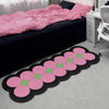 Pink and green cartoon decorative floor mat lying on a light gray carpet.