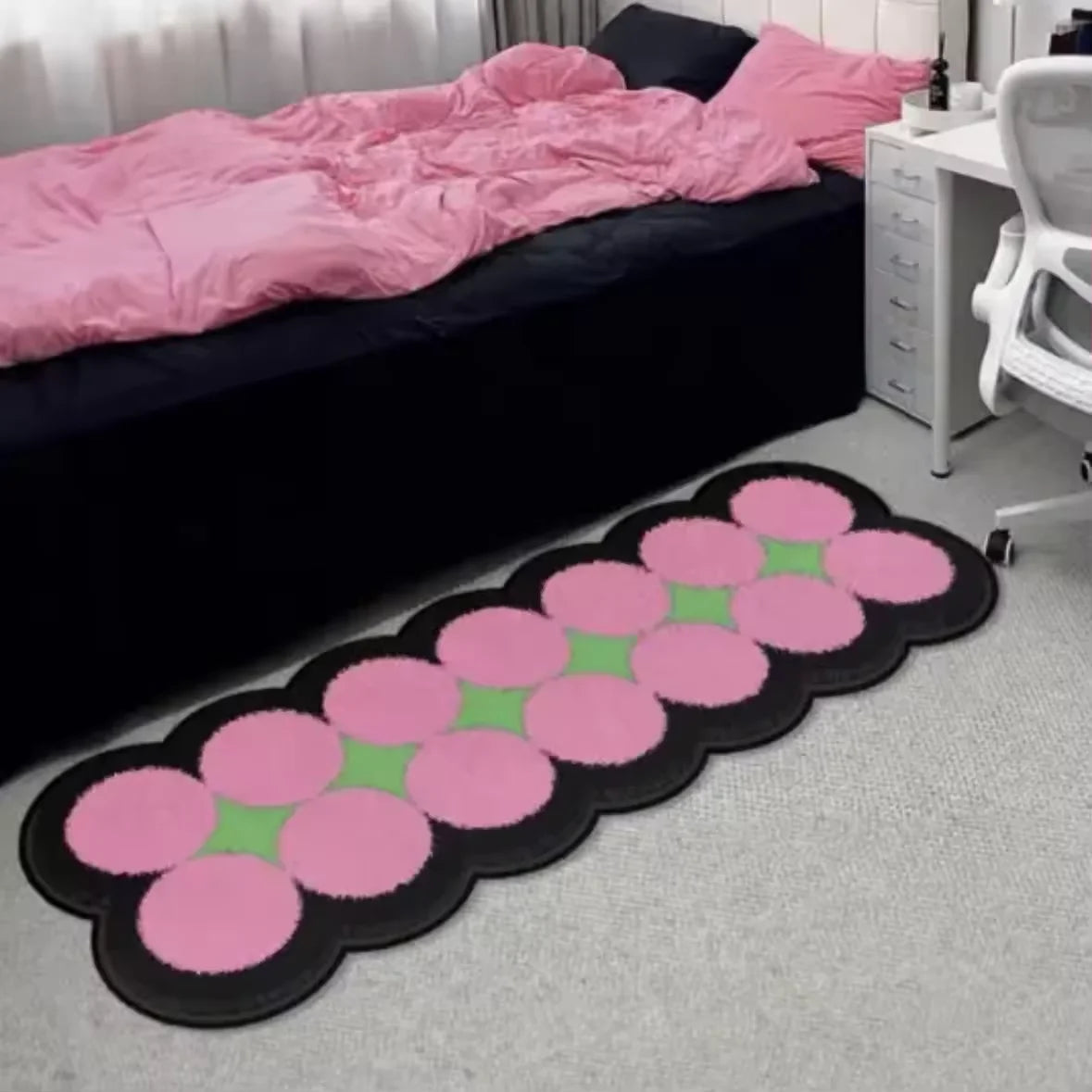 Pink and green cartoon decorative floor mat lying on a light gray carpet.