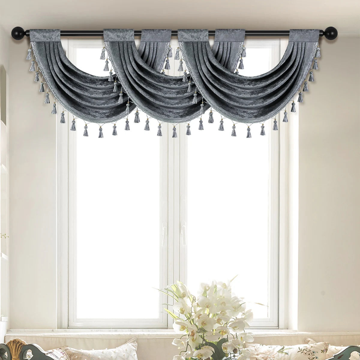 Gray European style window curtain valance with tasseled fringe hanging over a window.