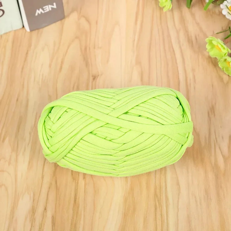 A ball of bright lime green flat thread yarn for crafting and sewing placed on a wooden surface.