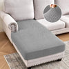 A gray jacquard stretch sofa cushion cover placed on a light-colored sofa and a rug.