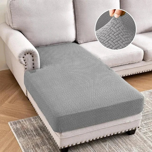 A gray jacquard stretch sofa cushion cover placed on a light-colored sofa and a rug.