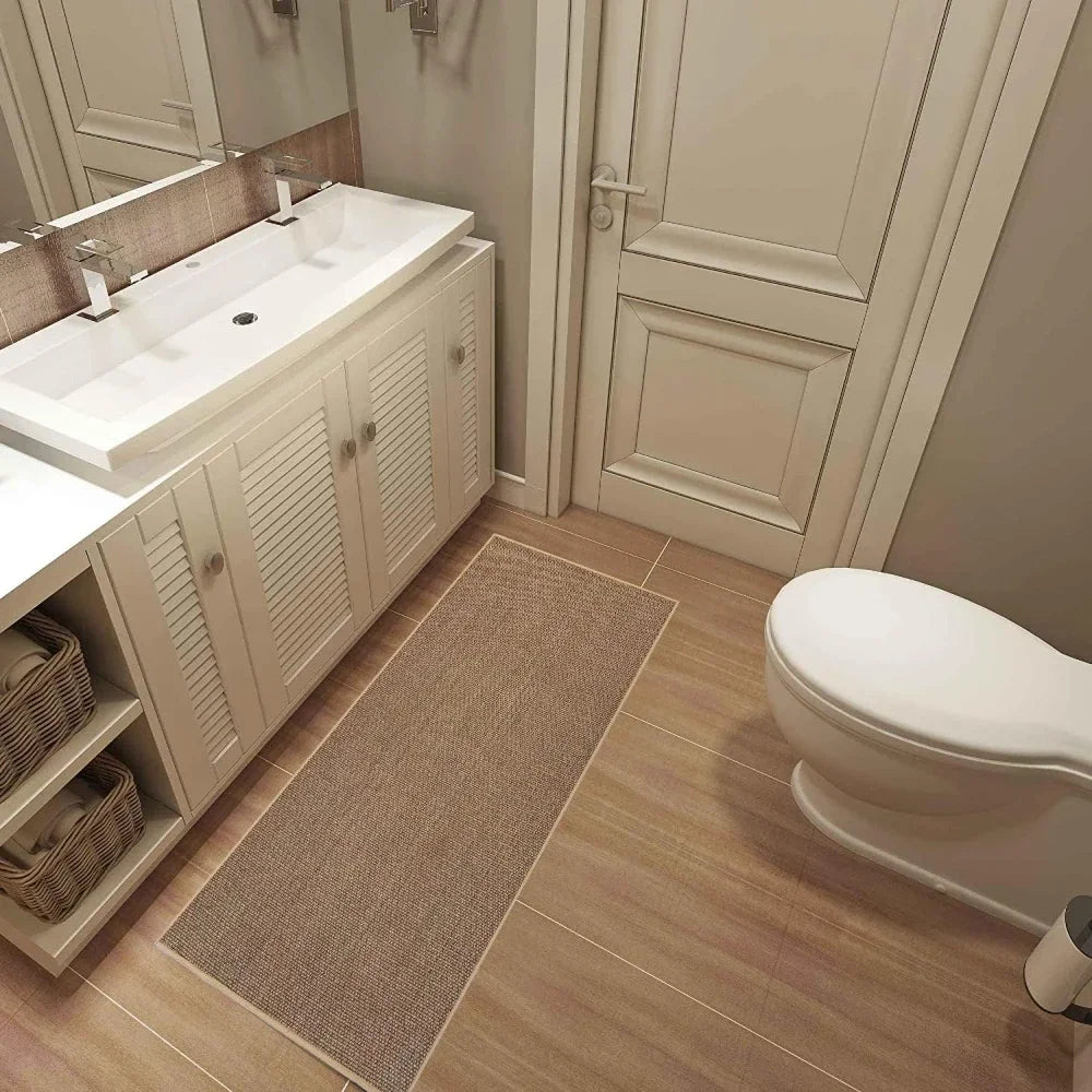 A rectangular beige non-slip faux sisal kitchen rug placed on a light wood floor.