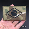 A tactical multicam flag patch is shown being held by a hand against a dark background.