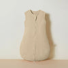 A beige muslin cotton baby sleeping bag with a front zipper, displayed against a light background.