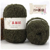 A pair of dark olive green soft coral velvet yarn balls for crafting with a label showing the product name and quantity