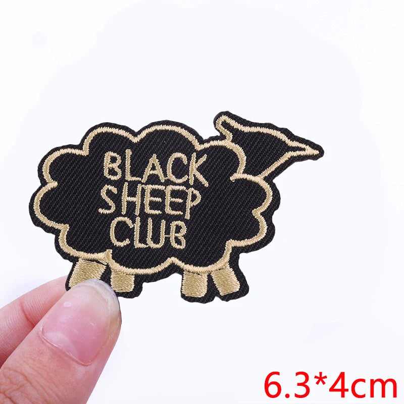 Black sheep club embroidered patch with gold stitching on a black fabric background